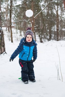 Küçük çocuk kartopu oynuyor. Kış açık hava aktivitesi.