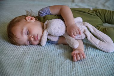 Uyuyan bebek Yumuşak bir peluş oyuncağa sarılıyor.