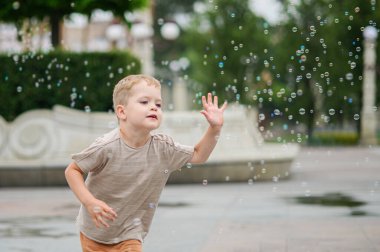 Mutlu çocuk dışarıda sabun köpüğüyle oynuyor..