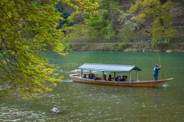 Kyoto, Japonya - 5 Nisan 2023: Tanımlanamayan insanlar Arashiyama ilçesinde Katsura nehrinde yelken açan bir tekneye biniyorlar