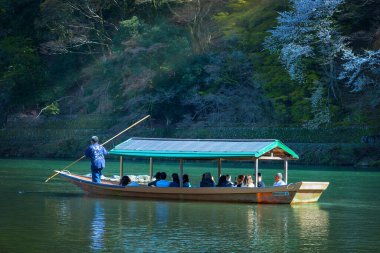 Kyoto, Japonya - 29 Mart 2023: Tanımlanamayan kişiler Arashiyama ilçesinde Katsura nehrinde yelken açan bir tekneye biniyorlar