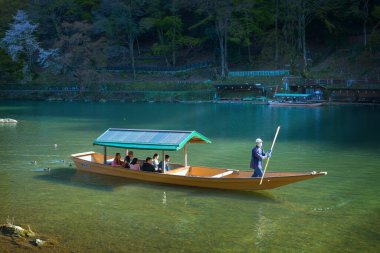 Kyoto, Japonya - 29 Mart 2023: Tanımlanamayan kişiler Arashiyama ilçesinde Katsura nehrinde yelken açan bir tekneye biniyorlar