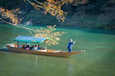Kyoto, Japonya - 29 Mart 2023: Tanımlanamayan kişiler Arashiyama ilçesinde Katsura nehrinde yelken açan bir tekneye biniyorlar