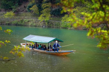 Kyoto, Japonya - 5 Nisan 2023: Tanımlanamayan insanlar Arashiyama ilçesinde Katsura nehrinde yelken açan bir tekneye biniyorlar