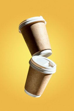 Üzerinde havalanan bir kahve bardağı olan bir poster. Bir kahve dükkanı için yaratıcı bir model. Sarı arkaplan