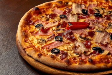 Tahta tahtada jambonlu, peynirli ve zeytinli İtalyan pizzası. İtalyan mutfağı. Yakın plan.