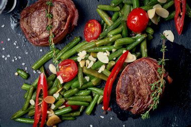 Siyah tahtada sebze garnitürlü fileminyon biftek. Yakın çekim, seçici odaklanma