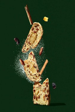 Stollen 'la kompozisyon. Uçan pudra şekeri ve malzemelerle çalınan parçalar dengesi. Yeşil arka plan. Yeni Yıl