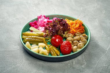 Ukrainian assorted pickled vegetables in a plate on a concrete background. Close-up