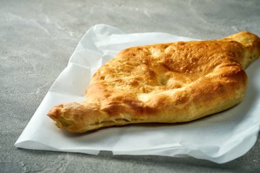 Baked Shotis puri on parchment. Concrete background