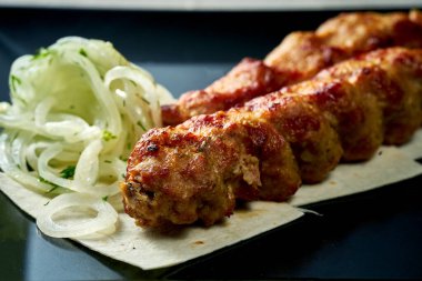 Fried Lula kebab on a skewer cooking on fire. Concrete background