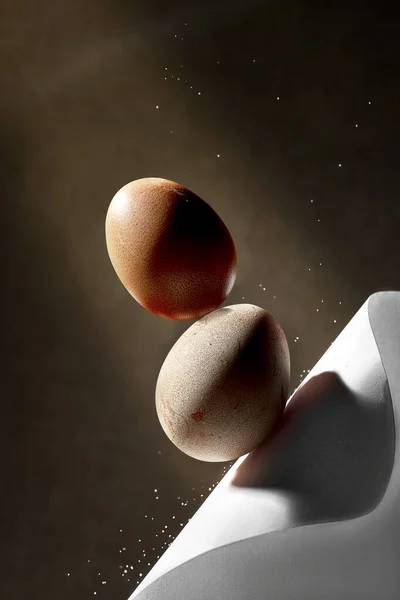Aesthetic composition with balancing chicken eggs on a brown background. Creative poster for Easter