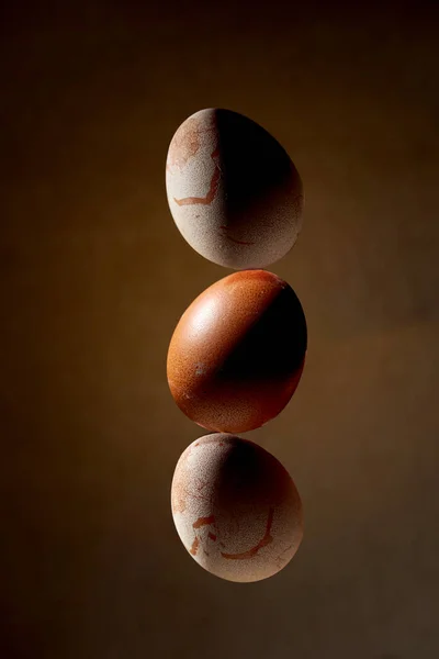 Aesthetic composition with balancing chicken eggs on a brown background. Creative poster for Easter
