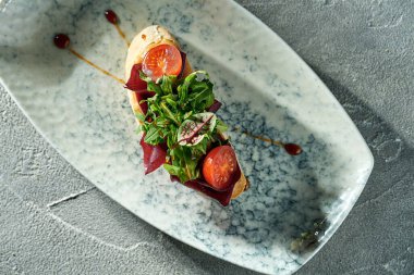 Vegetarian bruschetta with beets, tomatoes and arugula in a plate on a concrete background.