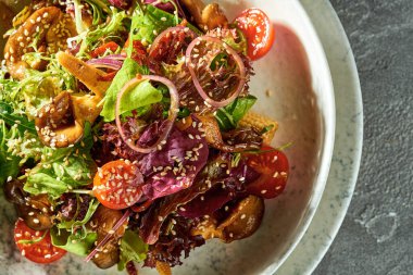 Salad with tomatoes, mushrooms and corn in a plate on a concrete background. Vegetarian food