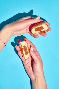 Bir kadın eli mavi bir arka planda kesik bir mochi tutuyor.