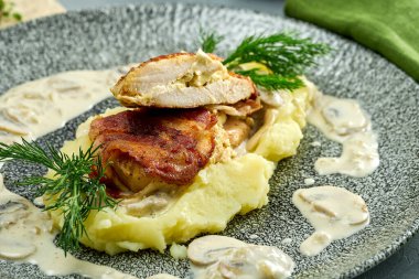 Fırında tavuk göğsü, patates püresi ve tabakta mantar sosu.