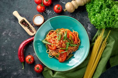 Domatesli makarna, kuşkonmaz ve arka planda kırmızı sos..