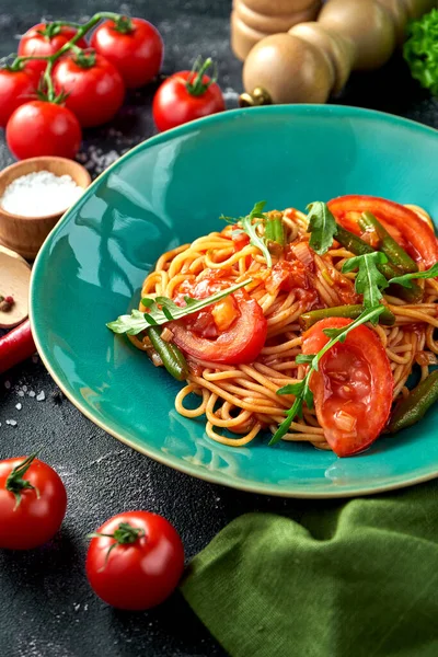 stock image Pasta with tomatoes, asparagus and red sauce in a plate on a dark background.