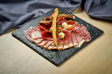 Ahşap arka planda etli atıştırmalık bir tabak.