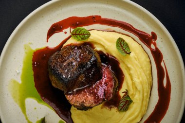 Böğürtlen soslu fileto ve tabakta patates püresi.