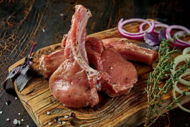 Kemiğin üzerinde marine edilmiş taze domuz eti ve ahşap bir tahtada baharatlar.