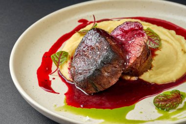 Böğürtlen soslu fileto ve tabakta patates püresi.