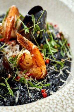 Lokantanın içindeki tabakta midye, karides ve mürekkep balığı mürekkebi olan siyah risotto. Mesaj için yer. Menü için fotoğraf. Kapat.