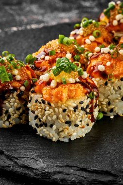 Siyah arka planda karides ve somonlu fırında suşi rulosu. Japon yemeği, menü için fotoğraf