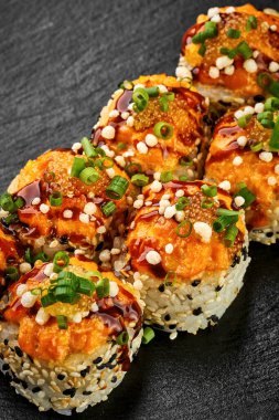 Siyah arka planda karides ve somonlu fırında suşi rulosu. Japon yemeği, menü için fotoğraf