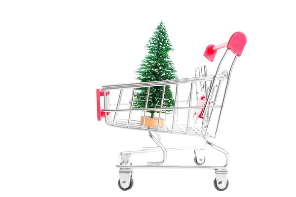 コピースペースの白い背景に隔離されたミニチュアプッシュカートに置かれた人工的なおもちゃのクリスマスツリー 新年小道具の買い物 — ストック写真