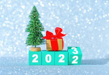 Yeni yıl 2023 başlangıç konsepti: yarım yamalak ahşap blok, oyuncak noel ağacı ve ışıl ışıl bir Noel geçmişine karşı süslü hediye kutusu.