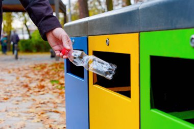 Kamu parkına yerleştirilmiş renkli çöp kutusuna plastik şişe atmak..