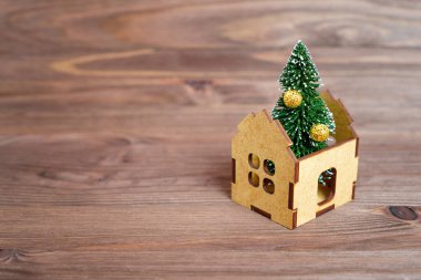 Oyuncak ahşap bir evin içine yerleştirilmiş uzun Noel ağacı heykelciği kopyalanmış ahşap bir arka planda izole edilmiş. Doğru Noel ağacını seçiyorum..