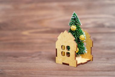 Tahta arka planda izole edilmiş bir oyuncak evin içine yerleştirilmiş uzun Noel ağacı heykelciği. Doğru yeni yıl ağacını seçiyorum.