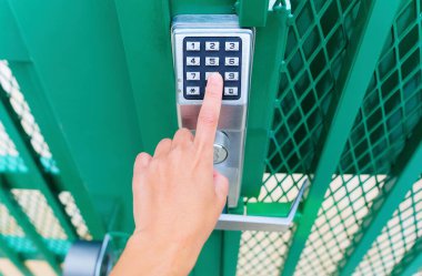Finger presses a digit on a keypad to open the mechanical code lock outdoors