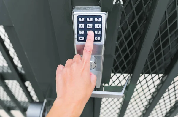 Hand enters a code to open a mechanical keypad gate lock