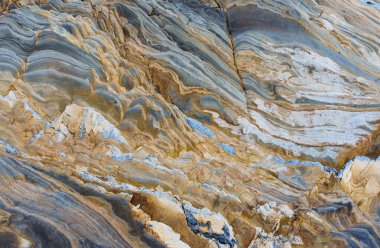 Natural backdrop of layered rocks in mesmerizing shades of gold and blue. Intricate and beautiful pattern creates a captivating visual effect.