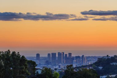 Vibrant beauty of Los Angeles downtown at sunset. The sky is ablaze with a spectrum of colors, providing a breathtaking backdrop for the towering buildings and city skyline.
