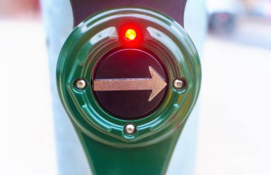 Kırmızı ampulle aydınlatılmış yaya geçidindeki yeşil yaya sinyal düğmesine yakın plan..