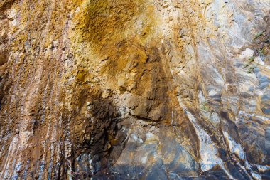 Malibu sahilinin kayalık kıyı şeridinin engebeli güzelliği. Kalıplaşmış taş duvar yükselir ve dramatik bir doğal arka plan yaratır..