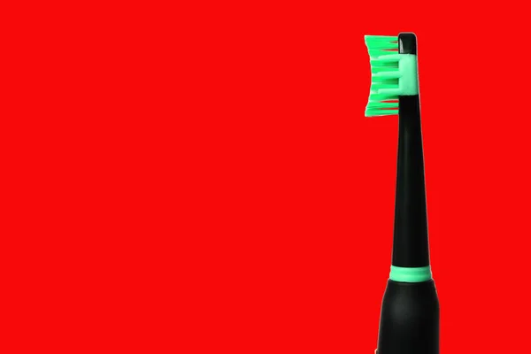 带有绿色软毛的黑色电动牙刷在红色背景下与复制空间隔离的特写 — 图库照片