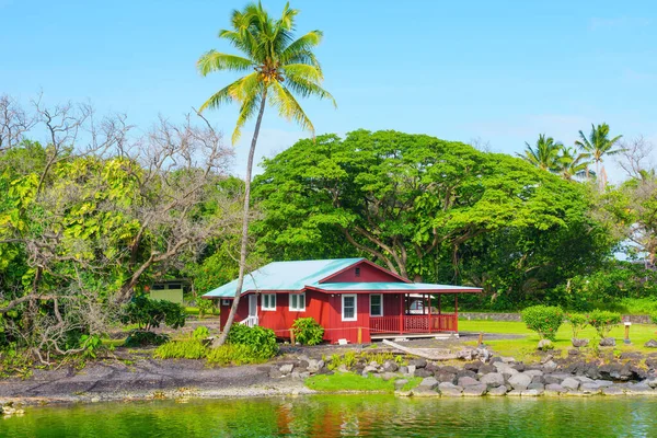 夏威夷一座清澈的湖畔有一座古朴的红屋 郁郁葱葱的绿叶和平静的湖水造就了宁静田园风光 使它成为一个完美的逃避和放松的地方 — 图库照片