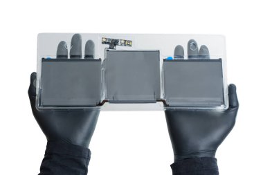 Bir çift siyah eldiven giymiş el, dizüstü bilgisayarın pilini değiştiriyor. Pil temiz plastiğe sarılıp dizüstü bilgisayara yüklenmeye hazır..