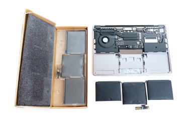 Parçalanmış dizüstü bilgisayar, şişmiş bir pil ile birlikte, beyaz arka planda hala izole durumda olan yepyeni bir yedek pil ile birlikte..