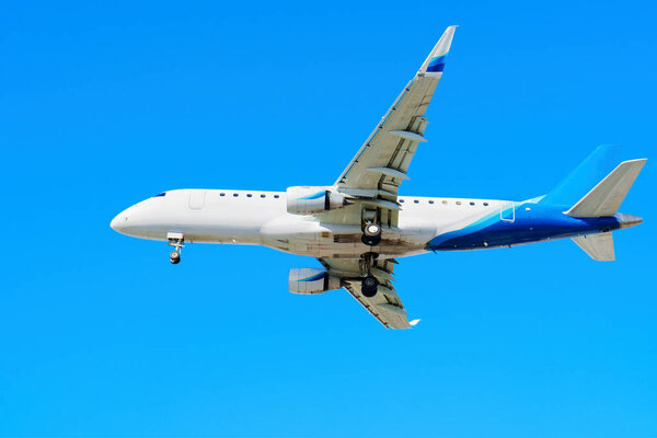Close-up side view of a plane as it comes in for landing against the blue sky background.