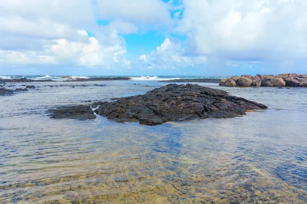 stock image Tranquil scene of Hawaii's volcanic coast, with a vast ocean horizon and rocky shoreline beneath wispy clouds.