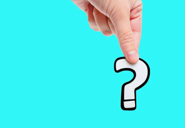 Large white question mark symbol in hand isolated on blue background with copy space. Uncertainty, confusion or skepticism related concept.