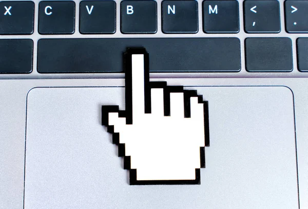 Blocky plastic hand-shaped mouse cursor model clicks space bar on the modern laptop\'s keyboard. Technology, education and e-commerce related concept.
