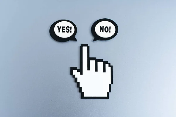 Plastic hand-shaped mouse cursor figurine and speech bubble shapes with YES and NO icons for selection on gray background. Decision-making, selection and user experience related concept.